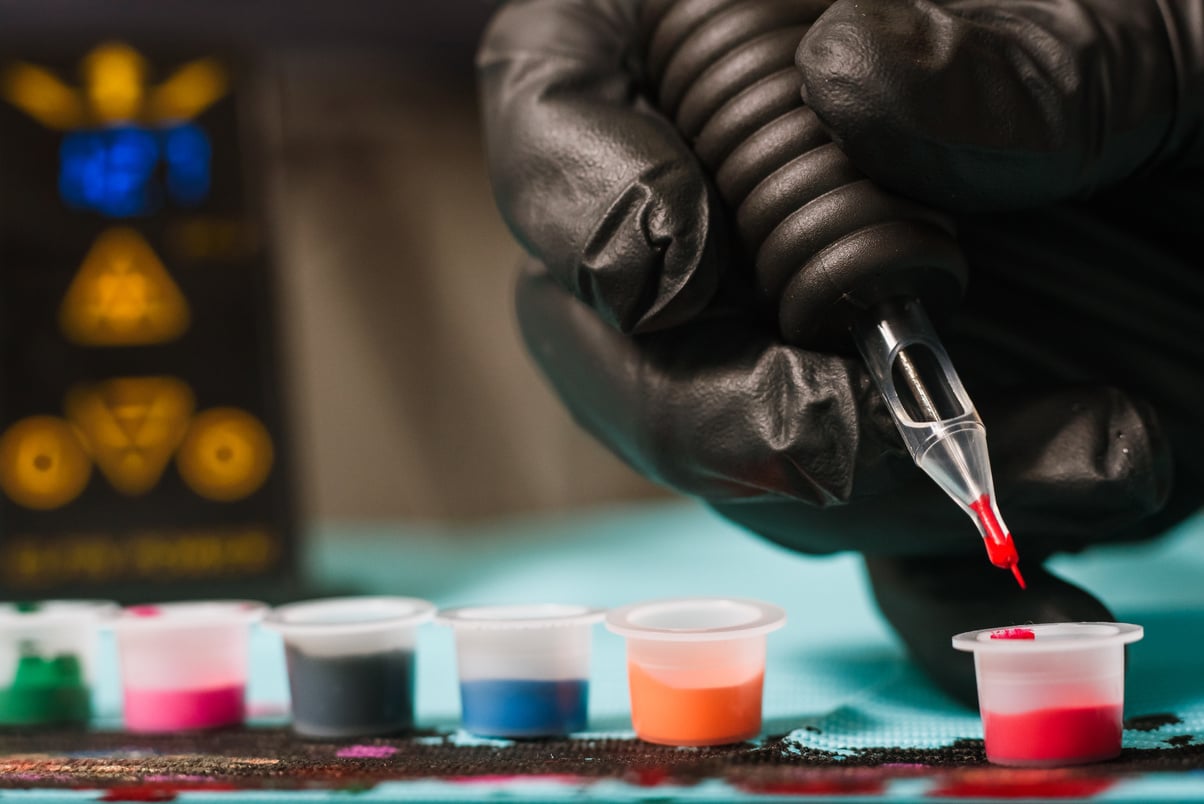 Tattoo artist refilling gun with ink